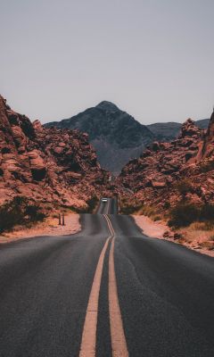 black concrete road surrounded by brown rocks wallpaper