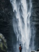 man standing near waterfalls wallpaper