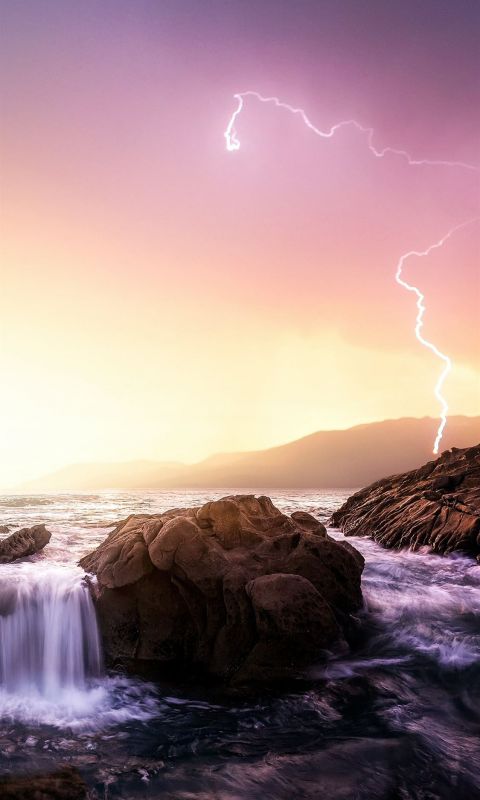 rock formation near sea under thunder light wallpaper